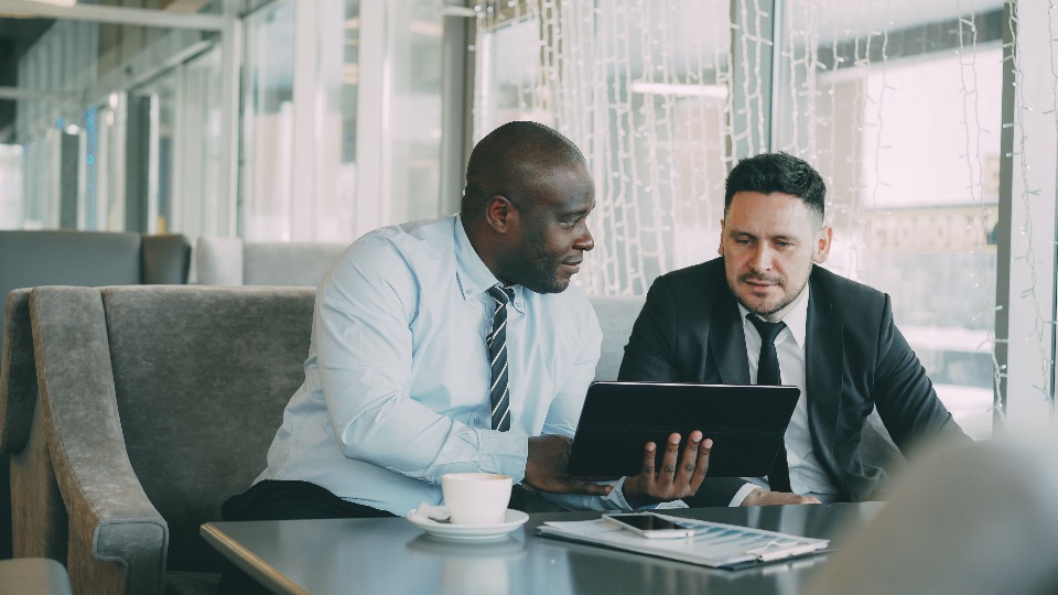 Two business professionals reviewing health insurance options together on a tablet