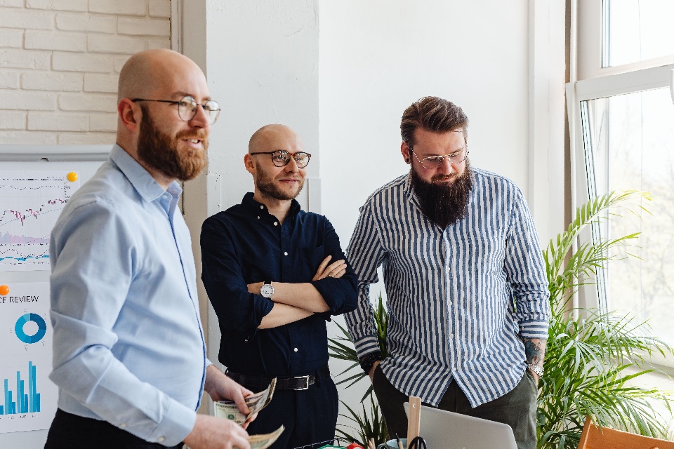 Three colleagues in a small business office reviewing performance charts